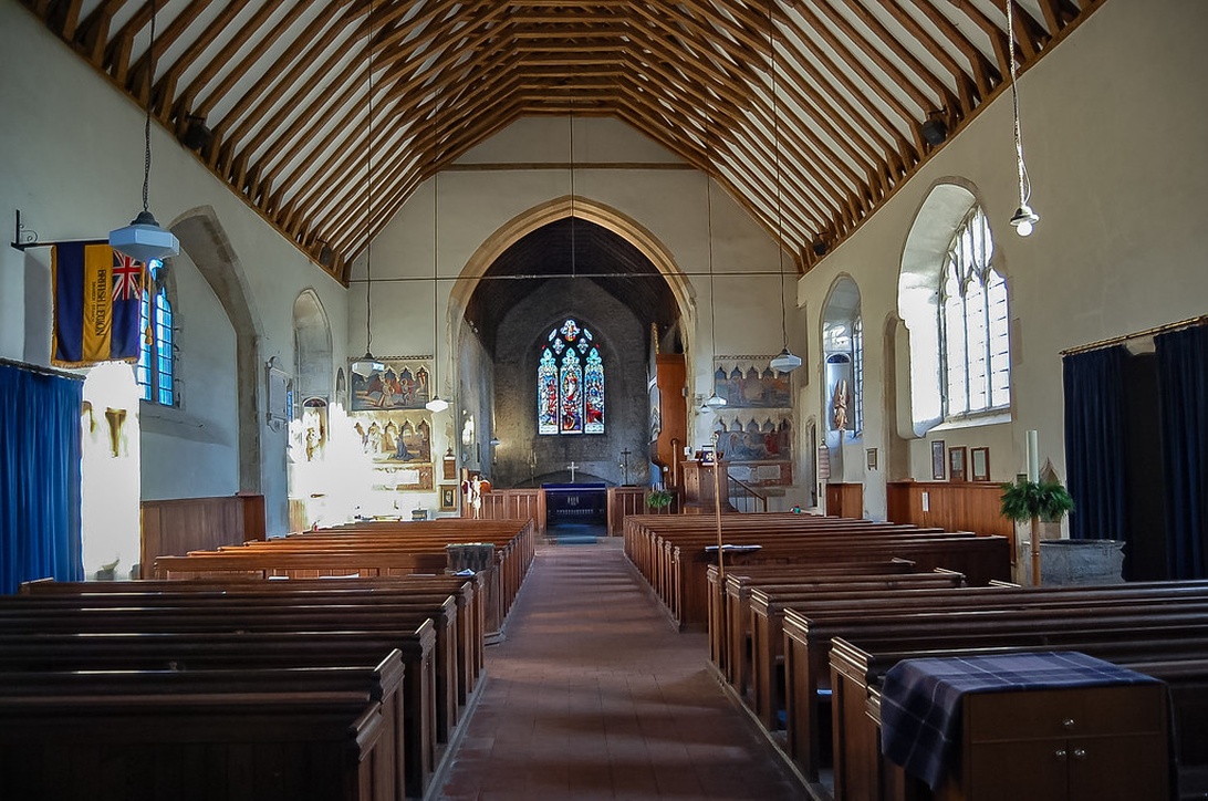 Intérieur d'une église avec une structure de plafond en poutres de bois remarquable.